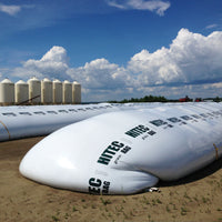 Large white grain bags by HITEC on a farm