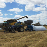 Unloading grain into HITEC grain bag in a recently harvested field